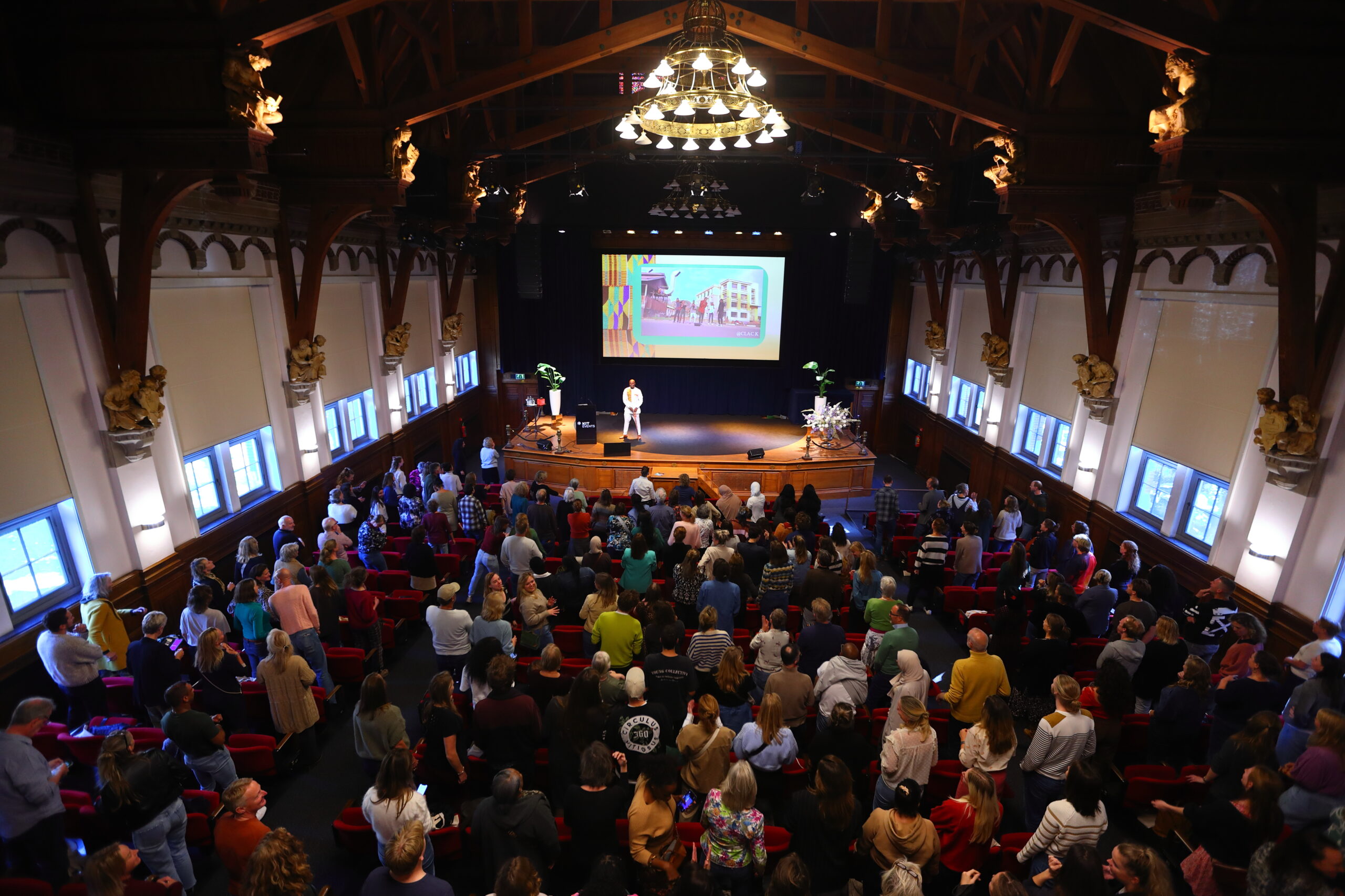 Andy Oppong geeft een keynote over diversiteit, inclusie en interculturele communicatie in een volle zaal.